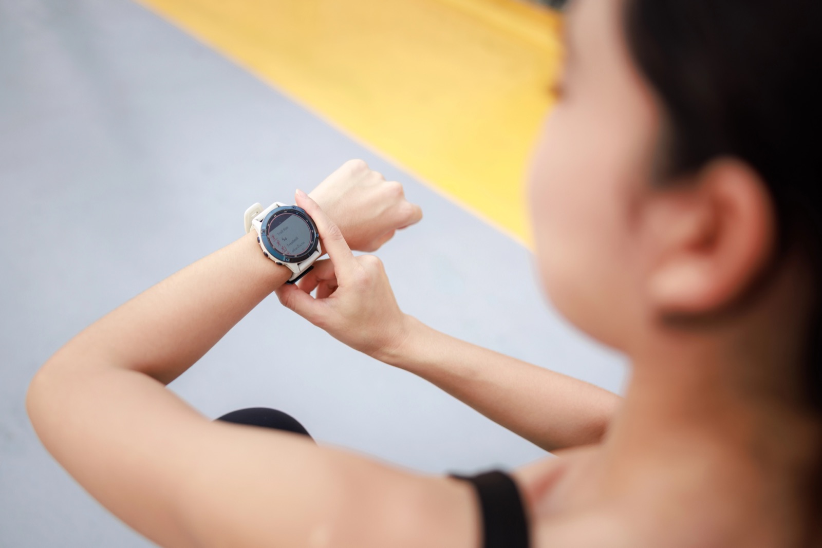 Young woman checking timer on wrist during jogging